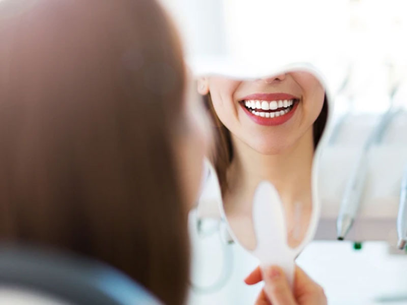 a woman checking her teeth in mirror