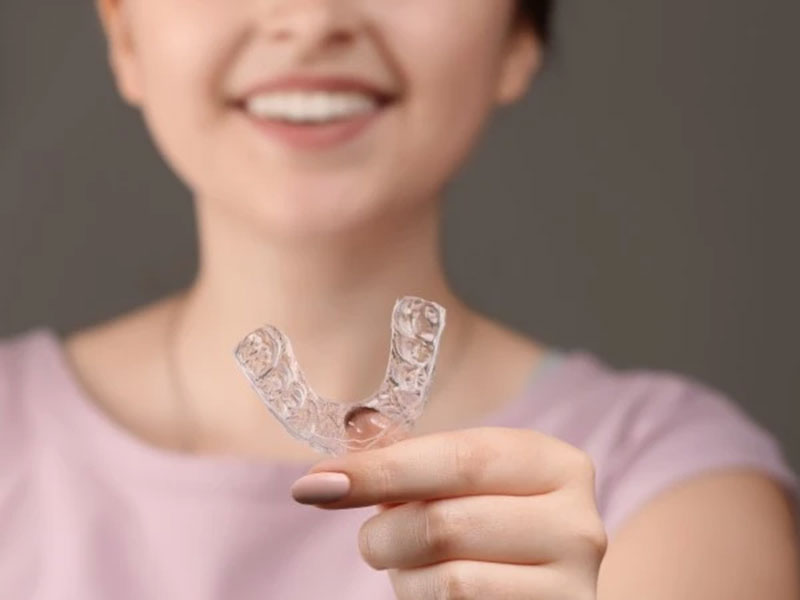 a woman holding teeth aligners