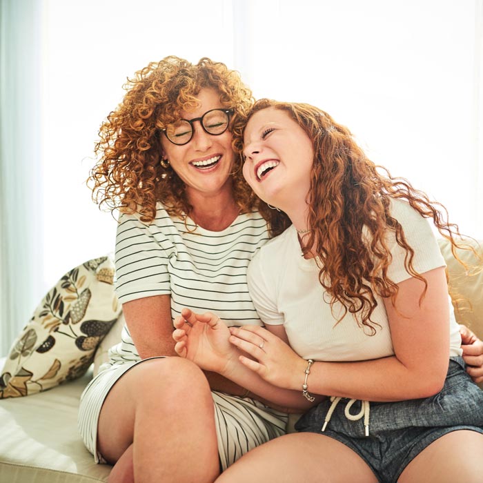 mother and daughter laughing on couch